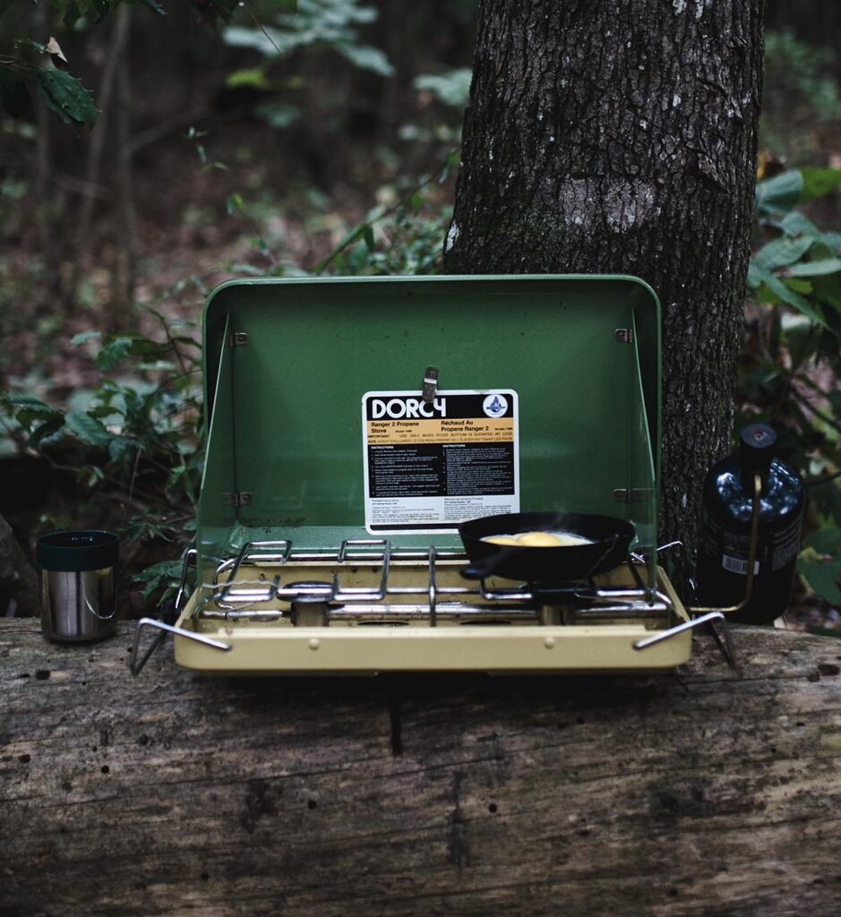 Portable propane camping stove on a log